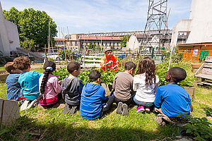 Un groupe de jeunes enfants écoute attentivement les conseils donnés par un jardinier.